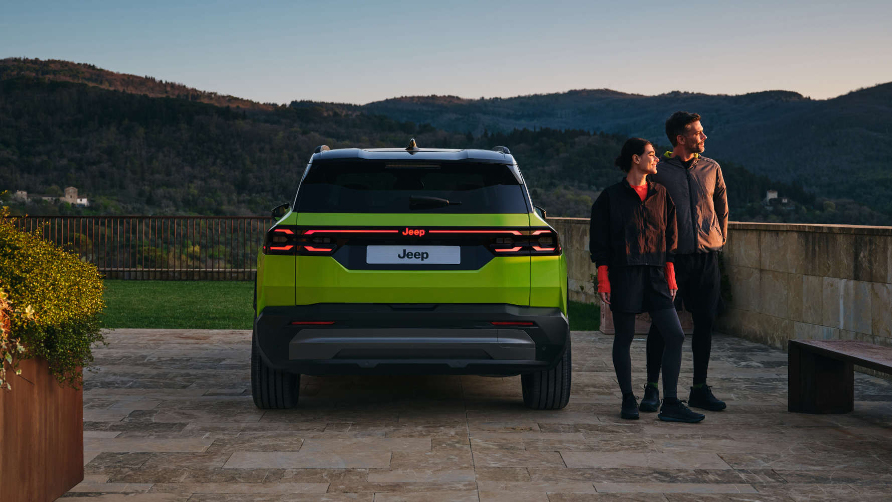 Jeep Compass яскраво-зеленого кольору, вигляд ззаду, чоловік і жінка поруч