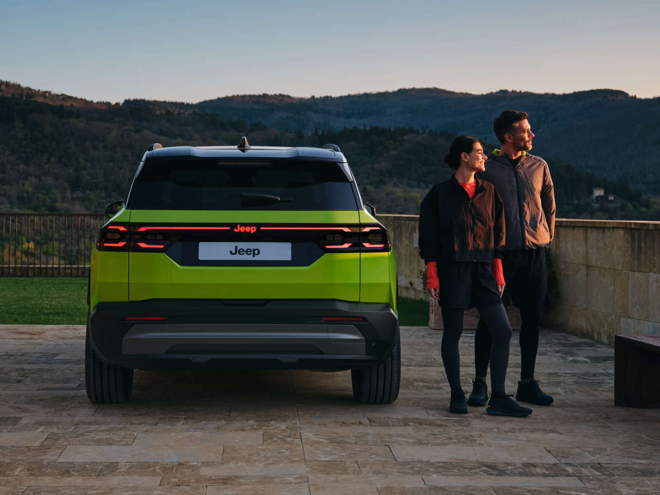 Jeep Compass яскраво-зеленого кольору, вигляд ззаду, чоловік і жінка поруч